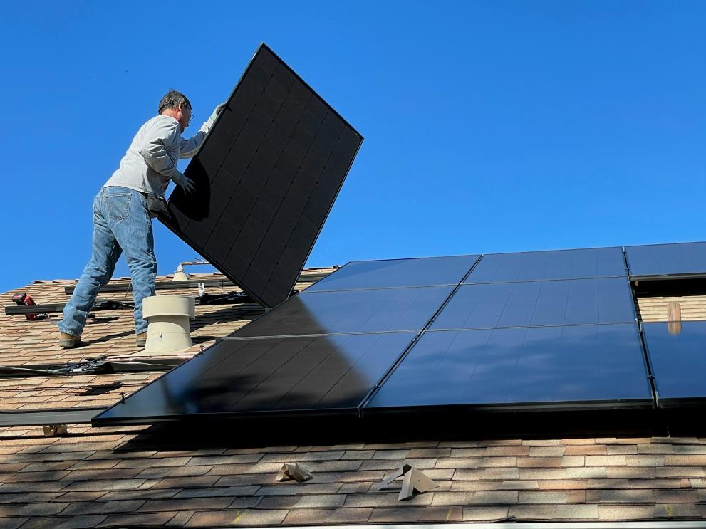 man on roof installing photovoltaic panels