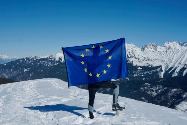 Man standing on snowy mountain displaying the EU flag